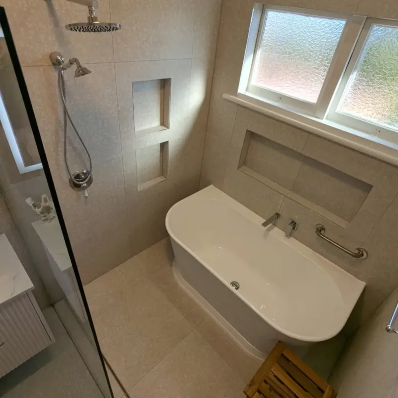 Belmont North: terrazzo-look 600 x 600 tiles behind a freestanding bath with a long tiled niche
