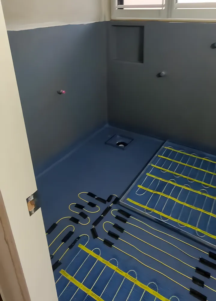 Charlestown bathroom: blue membrane over the whole floor with underfloor heating cables laid out and the shower niche framed in