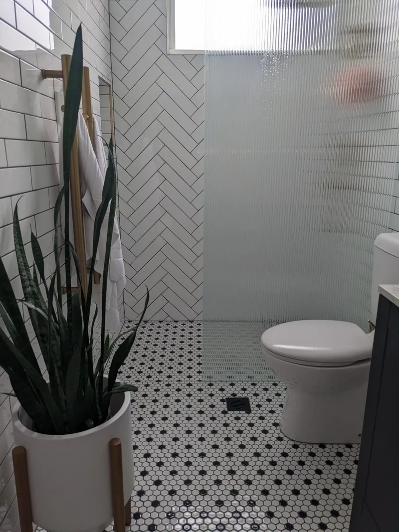 Black and white hexagon mosaic floor with a white herringbone shower wall and subway tiles
