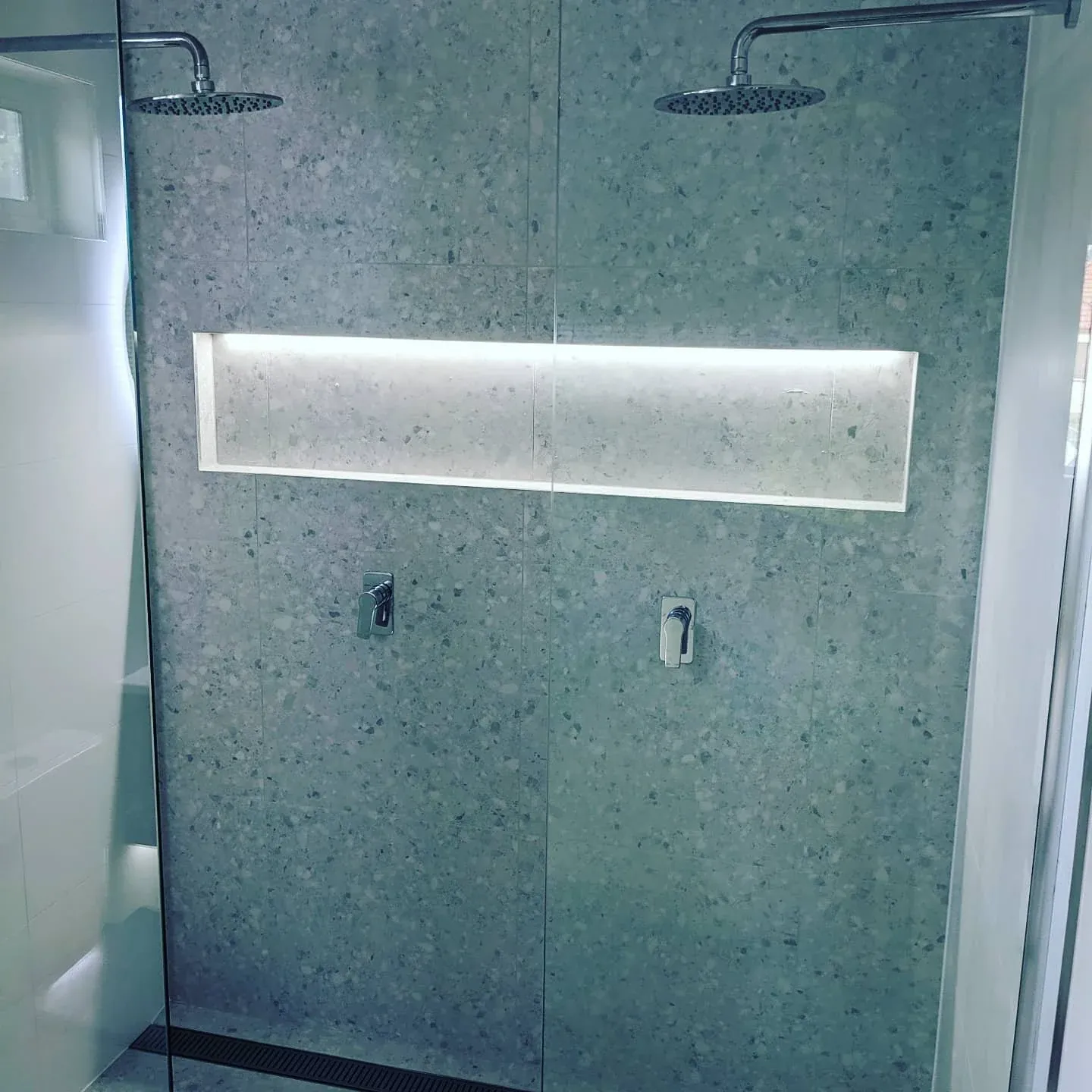 Terrazzo-look tiled wall with a long lit niche