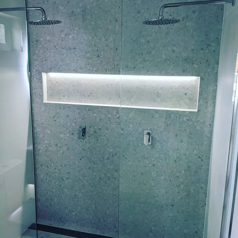 Terrazzo-look shower wall with a long lit niche
