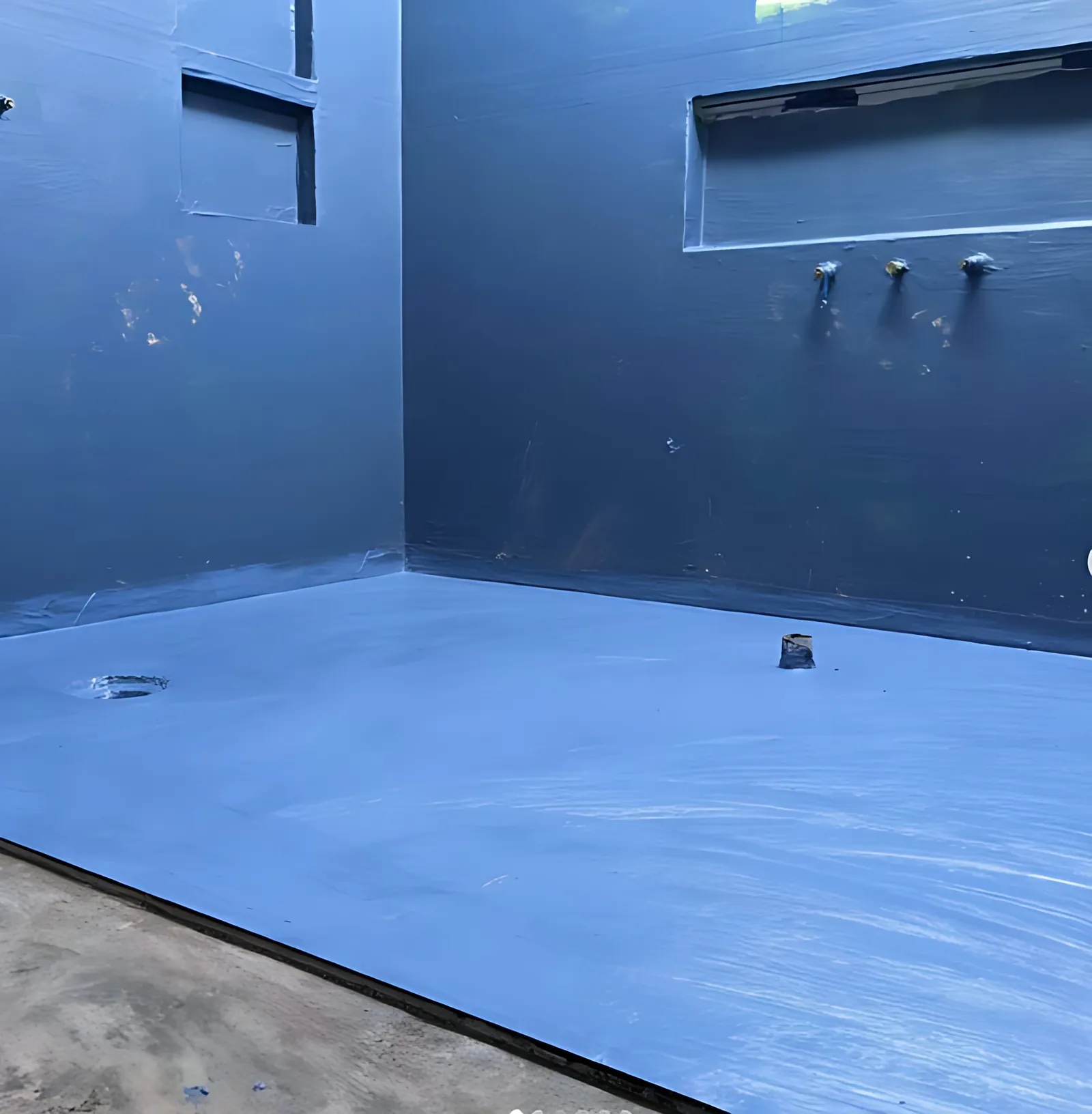 Shower recess coated in blue waterproofing membrane before tiling